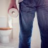 Man holding toilet paper roll in bathroom